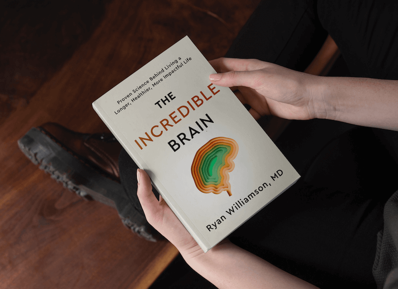 Man holding a copy of the Incredible Brain, a book written by Dr. Ryan Williamson M.D.